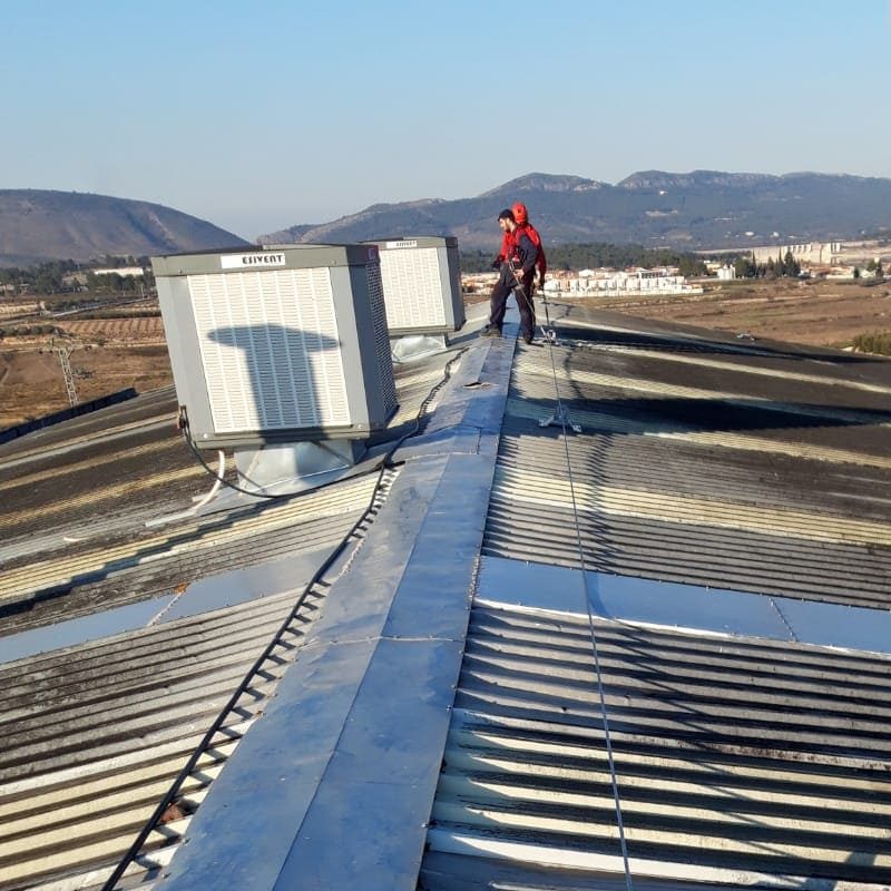Instalador montando y poniendo en marcha dos evaporativos EVA 422 instalados en el techo de una fábrica.
